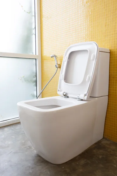 Witte flush toilet en gele wandversiering mozaïek — Stockfoto