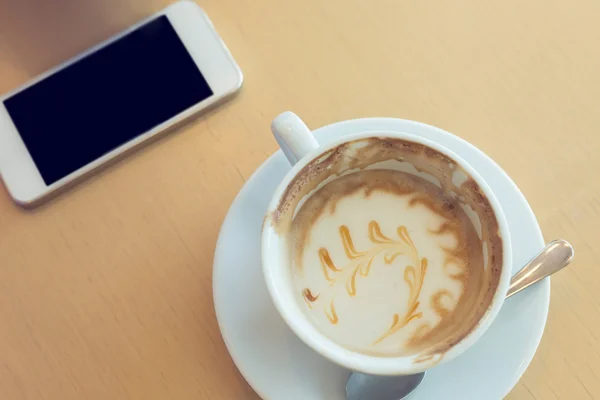 Café caramelo macchiato e telefone celular no café café — Fotografia de Stock