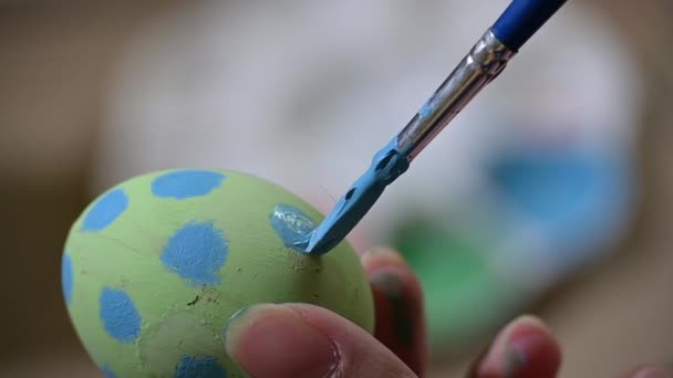 slow motion, people using brush painting dot blue color pattern design on green egg handicraft preparation for happy easter celebration