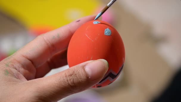 スローモーション 幸せなイースターお祝いのためのオレンジの卵の手工芸品の準備に筆画紫のパターンのデザインを使用して人々 — ストック動画