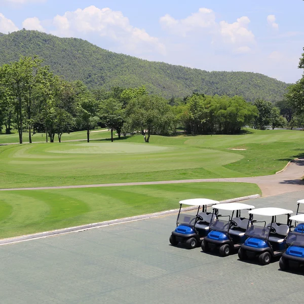 Carro de golfe no campo de golfe verde — Fotografia de Stock