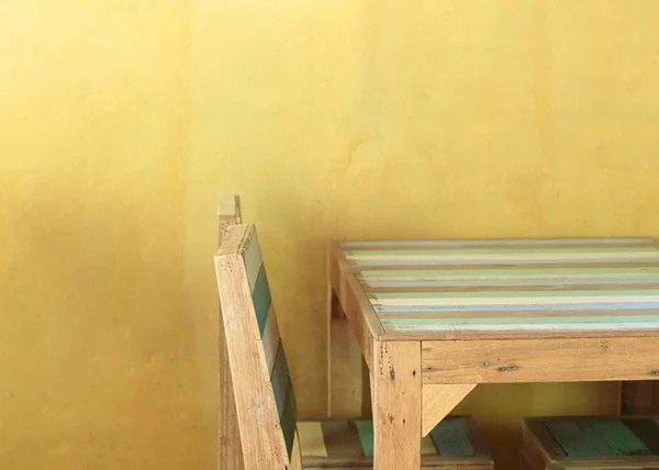 Tischholz im gelben Raum mit Mörtelwand — Stockfoto