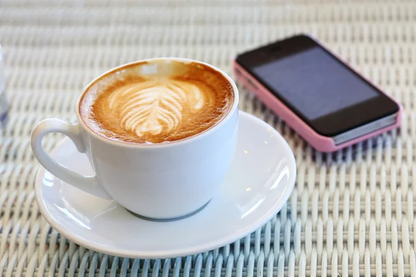 Coffee and mobile phone on white table in cafe — Stock Photo, Image