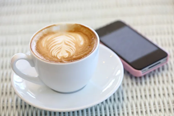 Coffee and mobile phone on white table in cafe — Stock Photo, Image