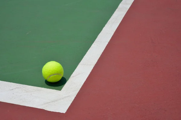 Теннисный мяч на зеленой площадке — стоковое фото