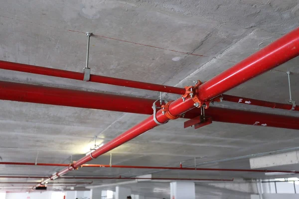 Red pipeline extinguishing water in industrial building — Stock Photo, Image