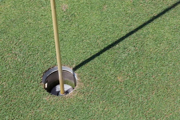 Отверстие для гольфа на зеленой траве с теневым флагом — стоковое фото