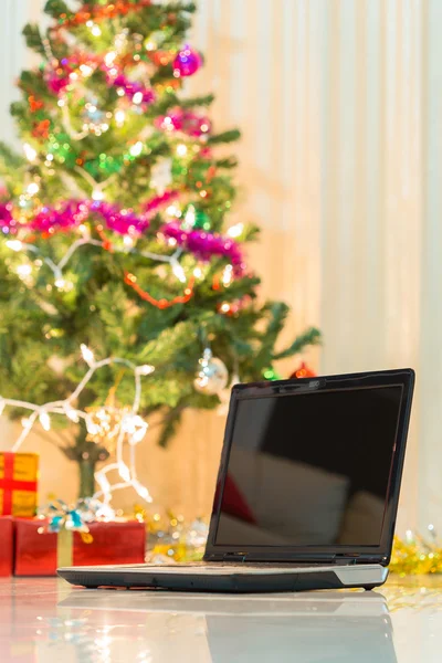 Laptop med presentförpackning och jul ljus bakgrund — Stockfoto