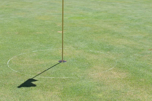 Golf hole on green grass with shadow flag Royalty Free Stock Images