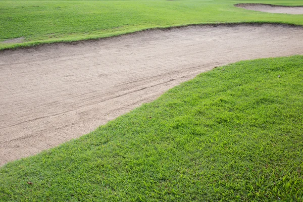Песчаный бункер и зеленая трава поля для гольфа — стоковое фото