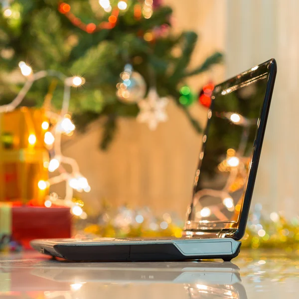 Laptop med presentförpackning och jul ljus bakgrund — Stockfoto