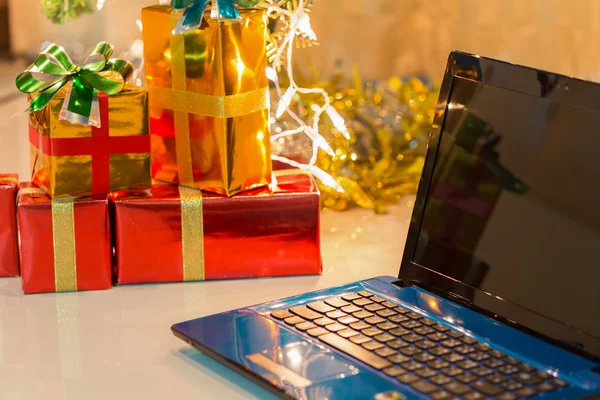 Laptop med presentförpackning och jul ljus bakgrund — Stockfoto