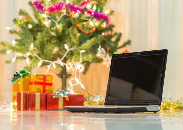 Laptop med presentförpackning och jul ljus bakgrund — Stockfoto