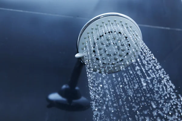 Douchekop in badkamer met waterdruppels stromend — Stockfoto