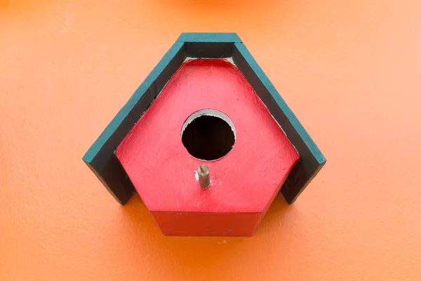 Kleurrijke vogel nest hout vak ingericht op oranje muur achtergrond — Stockfoto