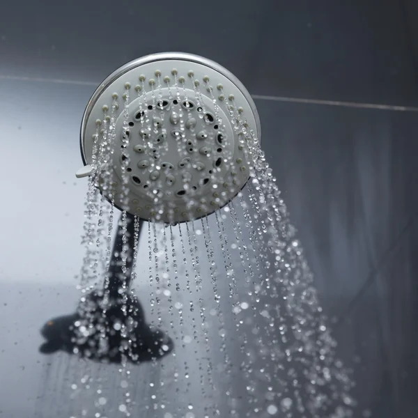 Douchekop in badkamer met waterdruppels stromend — Stockfoto