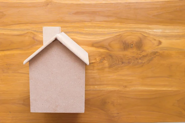 Piccolo modello di casa in legno su sfondo marrone in legno — Foto Stock