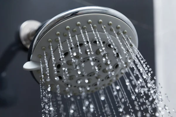 Douchekop in badkamer met waterdruppels stromend — Stockfoto