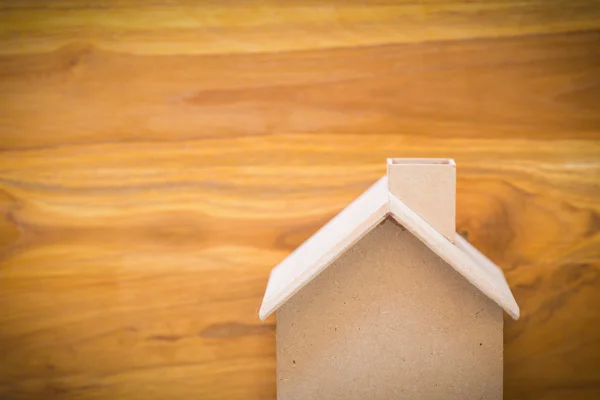 Small wood house model on brown wooden background — Stock Photo, Image