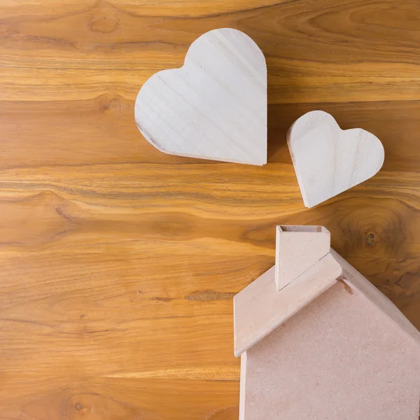 Drewniany dom i serce na brązowym tle drewna — Zdjęcie stockowe