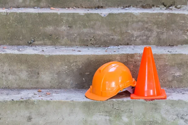 Oranje veiligheidshelm en kegel in bouwplaats — Stockfoto