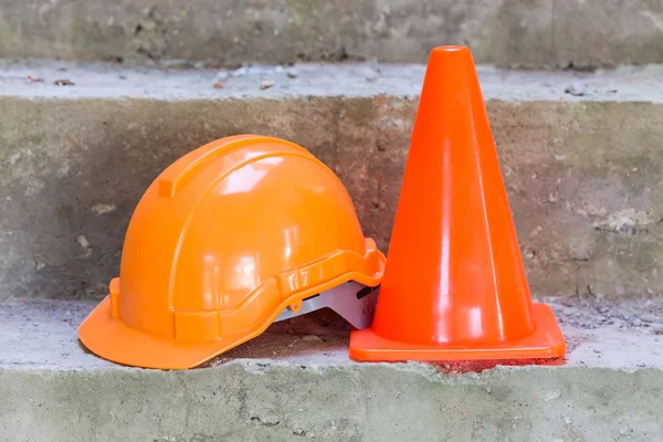 Oranje veiligheidshelm en kegel in bouwplaats — Stockfoto