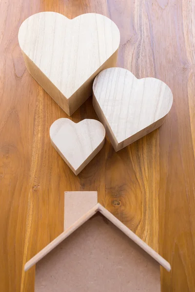 Wooden house and heart on brown wood background — Stock Photo, Image