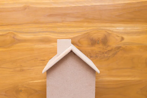 Domek dřevěný model na hnědé dřevěné pozadí — Stock fotografie