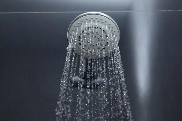 Duschkopf im Bad mit fließenden Wassertropfen — Stockfoto