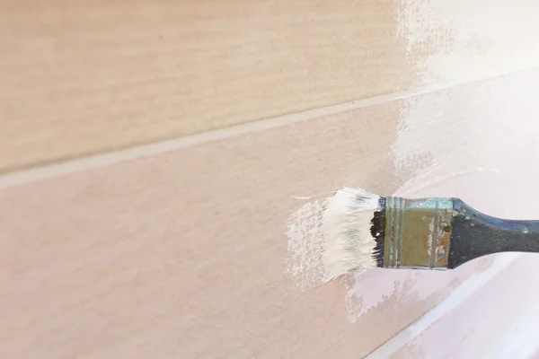 Paintbrush painting white on wood fence — Stock Photo, Image