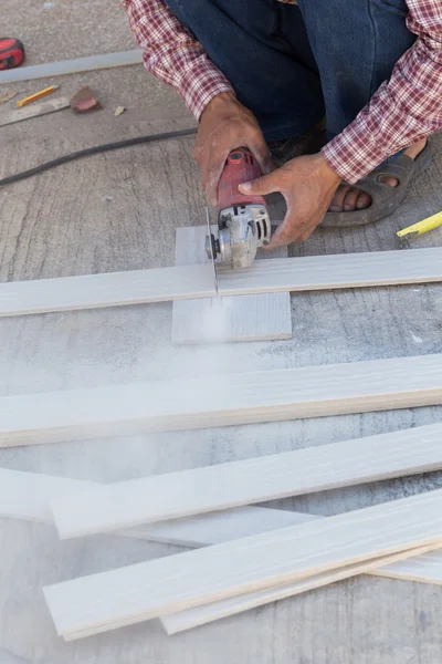 Manos de carpintero usando sierra eléctrica en madera en el sitio de construcción — Foto de Stock