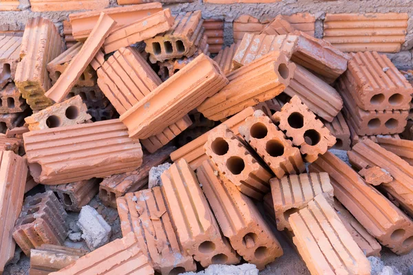 Pila de ladrillos en el sitio de construcción con fondo de pared de ladrillo — Foto de Stock