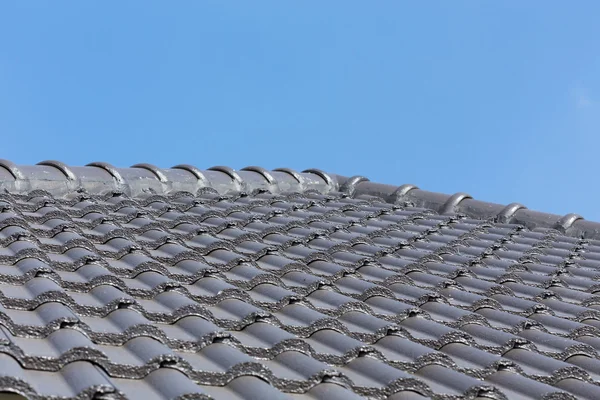 Zwarte dakpannen op huis met blauwe hemel — Stockfoto