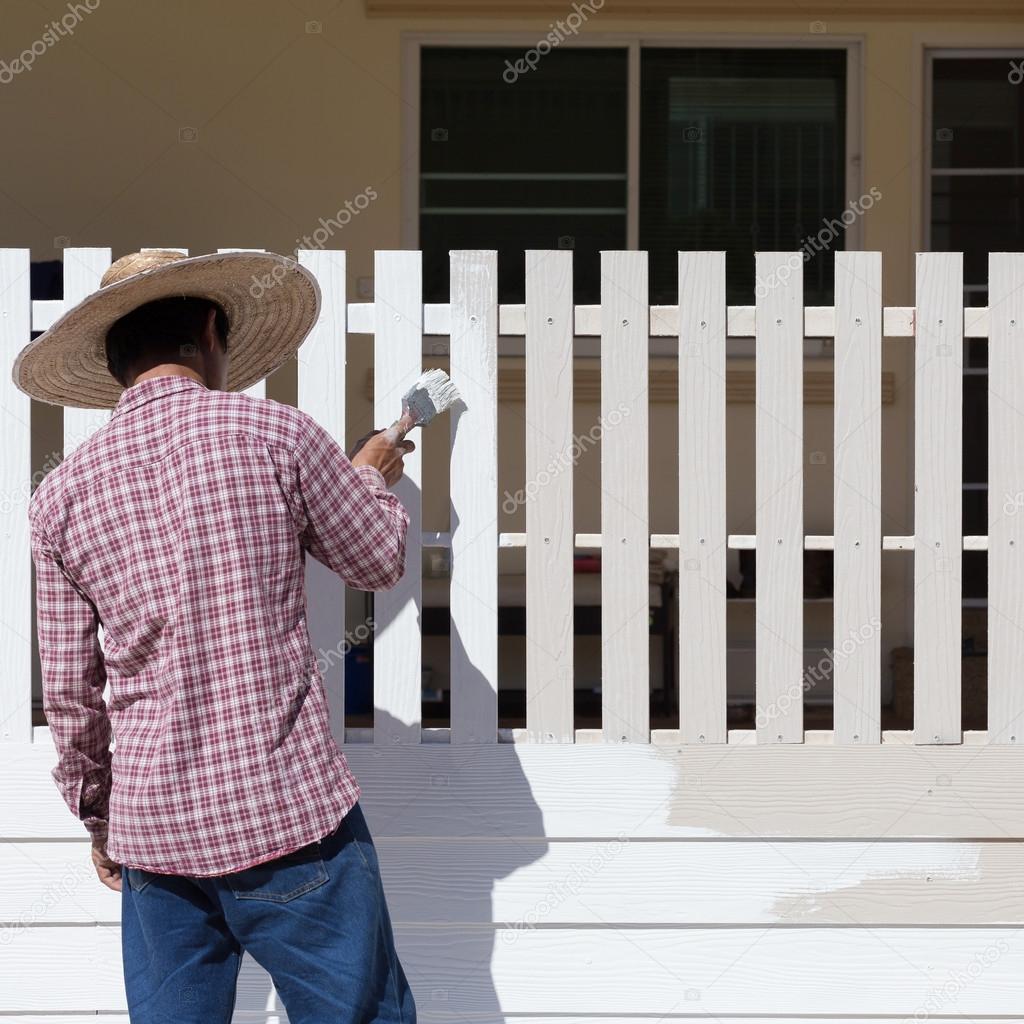 worker painted white fence with brush