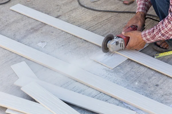 Mãos de carpinteiro usando serra elétrica em madeira no local de construção — Fotografia de Stock