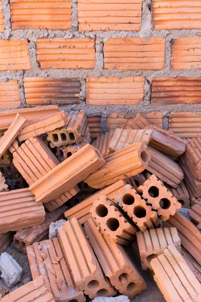 Pila de ladrillos en el sitio de construcción con fondo de pared de ladrillo — Foto de Stock