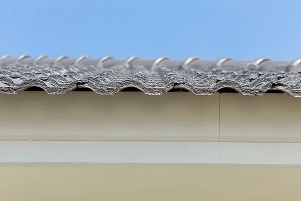 Azulejos del techo negro en casa con cielo azul —  Fotos de Stock