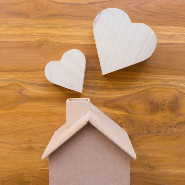 Wooden house and heart on brown wood background — Stock Photo, Image