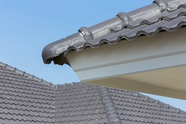 Zwarte dakpannen op huis met blauwe hemel — Stockfoto