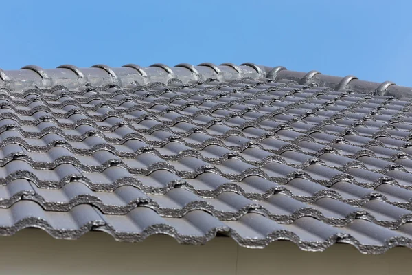 Azulejos del techo negro en casa con cielo azul —  Fotos de Stock