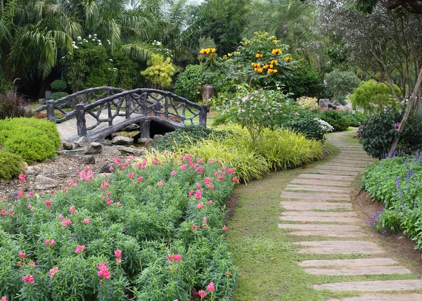 Landscape of floral gardening with pathway and bridge in garden — Stock Photo, Image