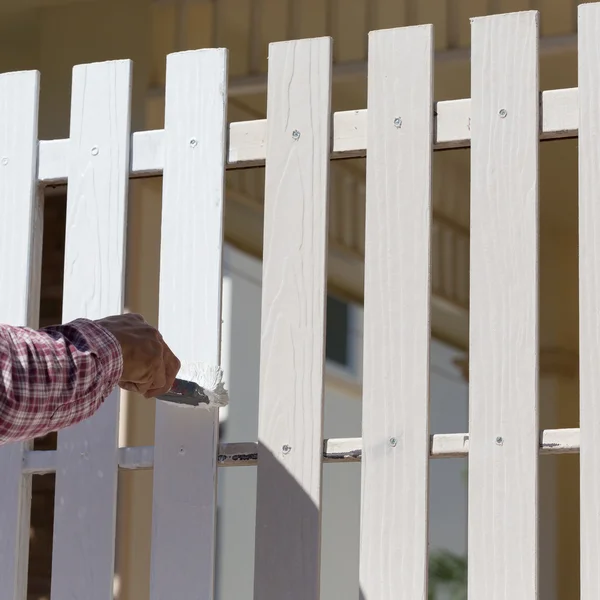 Hand worker holding brush painting white on wood fence — Stock Photo, Image