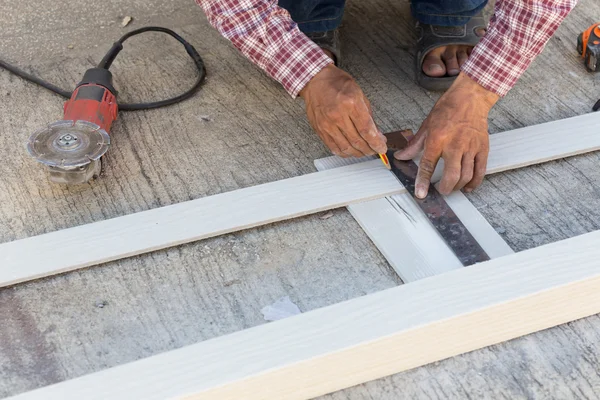 Carpintero usando regla para dibujar una marca de línea en un tablero de madera — Foto de Stock