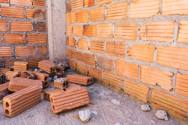 Pila de ladrillos en el sitio de construcción con fondo de pared de ladrillo — Foto de Stock