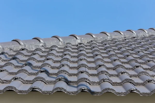 Zwarte dakpannen op huis met blauwe hemel — Stockfoto