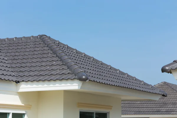 Azulejos del techo negro en casa con cielo azul — Foto de Stock