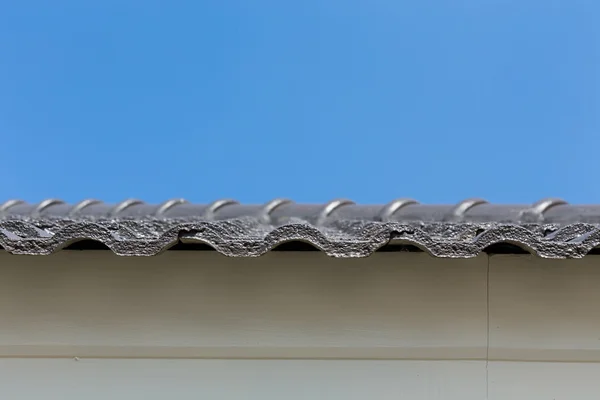 Чорна черепиця на даху на будинку з блакитним небом — стокове фото