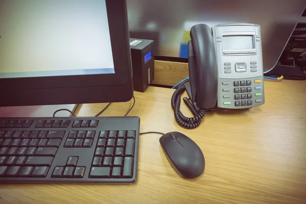 Mesa de trabajo en la oficina con el teléfono y el ordenador PC —  Fotos de Stock