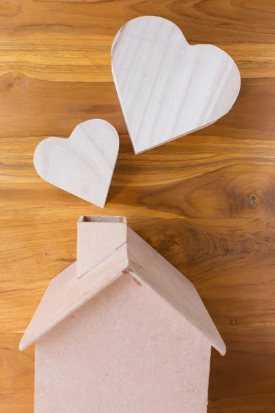 Drewniany dom i serce na brązowym tle drewna — Zdjęcie stockowe