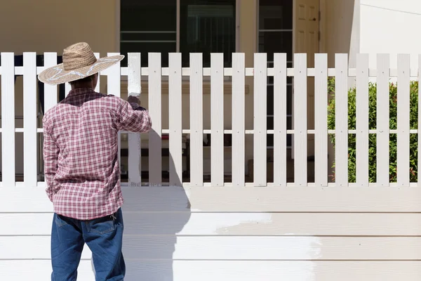 worker painted white fence with brush